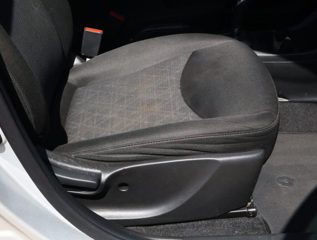 Dark fabric car seat with a red-trimmed seatbelt buckle visible beside it.