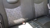 Back seat of a car with black upholstery and patterned fabric panels, headrests visible and a cup holder in the foreground.
