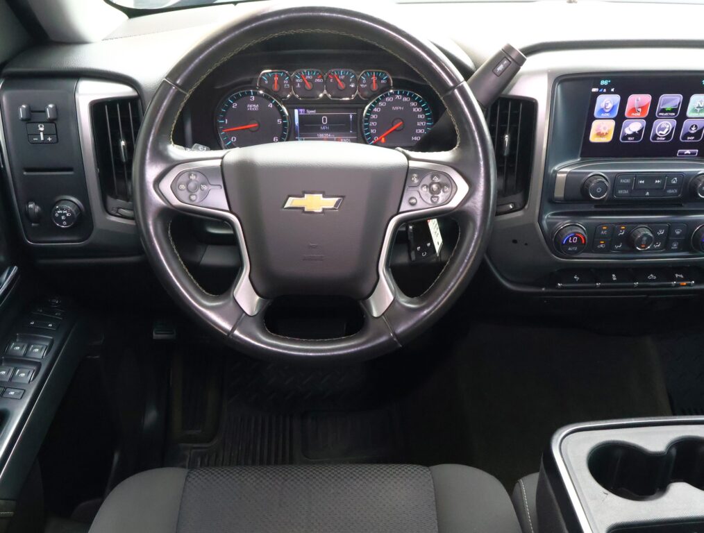 Interior of a Chevrolet vehicle showing the steering wheel with logo, digital instrument cluster, and a large center touchscreen panel on the right