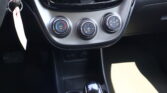 Center console of a car showing three round climate control dials and a glossy gear shifter; key ring is visible to the left.