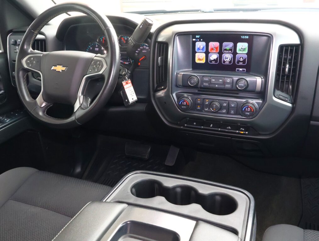 Interior view of a Chevrolet cabin featuring steering wheel, instrument cluster, and a central touchscreen with app icons plus climate controls below