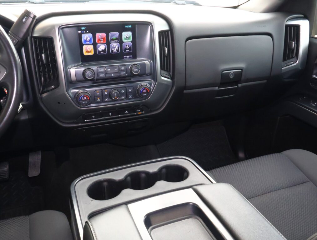 Interior of a vehicle showing the central dashboard with a touchscreen display, climate controls, and cupholders.