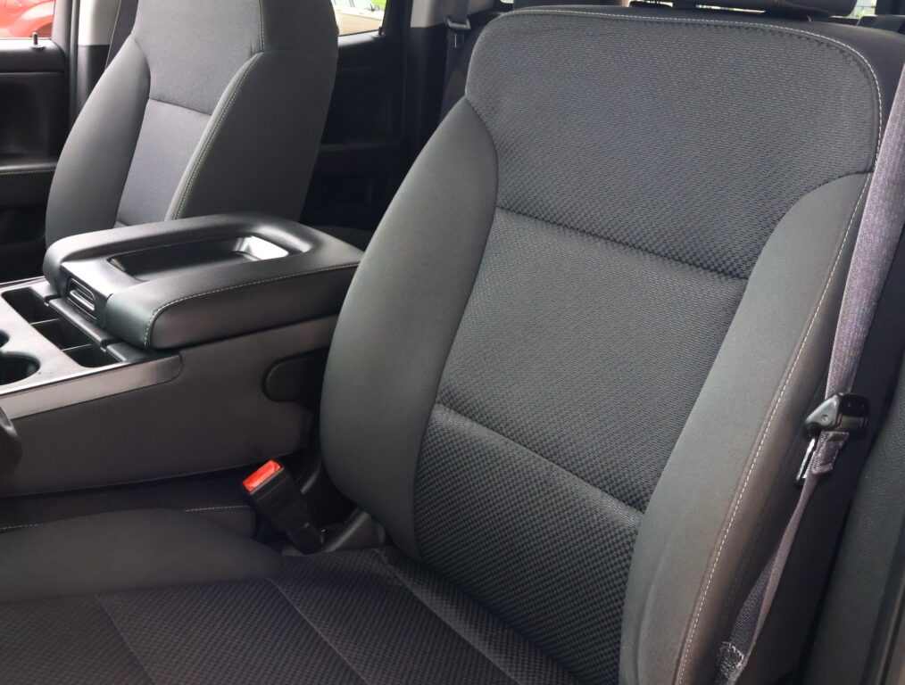 Dark gray fabric car seats in a vehicle, with a center armrest and cup holders visible between the front seats.