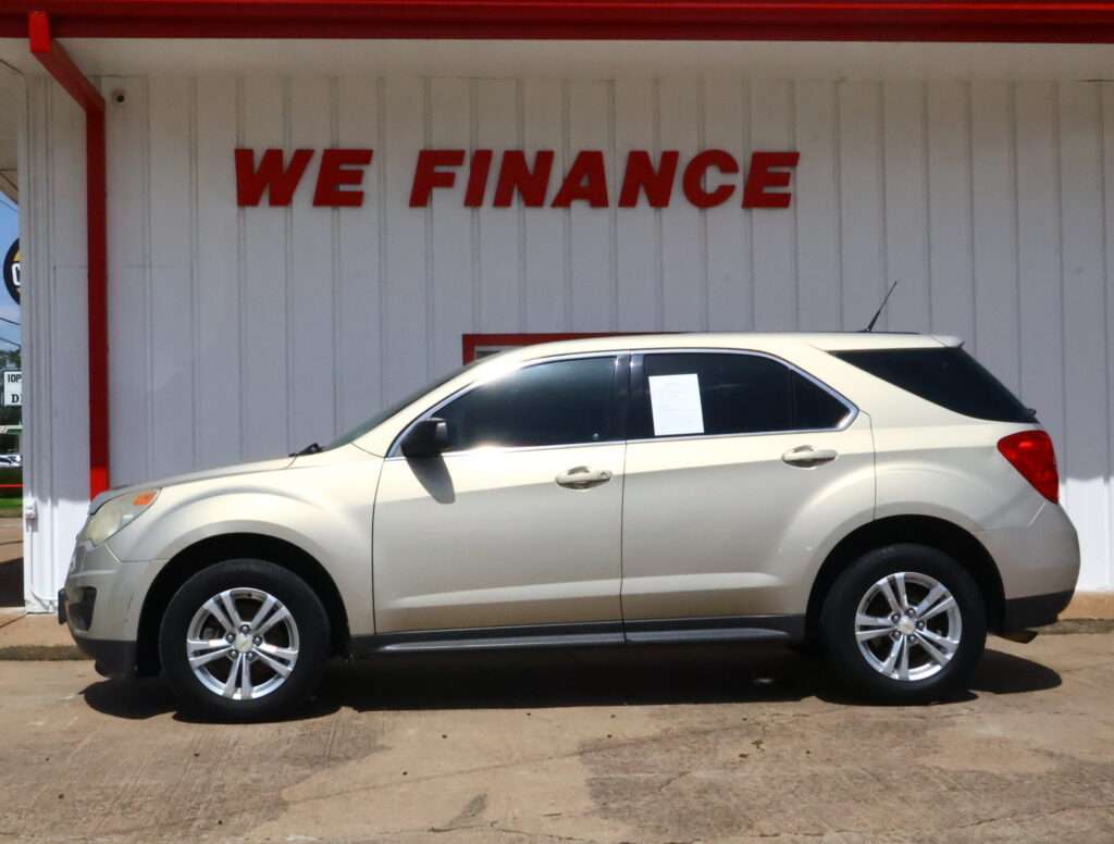 Beige SUV parked in front of a white wall with large red 'WE FINANCE' lettering above it to indicate financing.