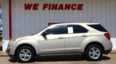 Beige SUV parked in front of a white wall with large red 'WE FINANCE' lettering above it to indicate financing.