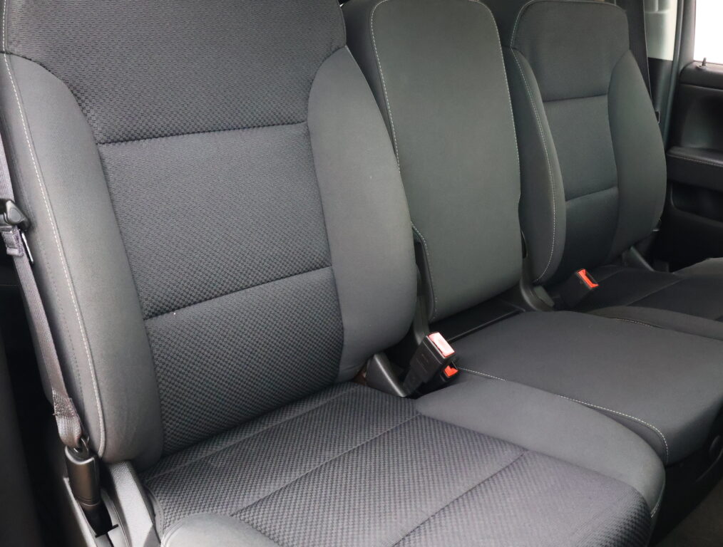 Dark gray car back seat with three seating positions and visible seat belts and stitching.