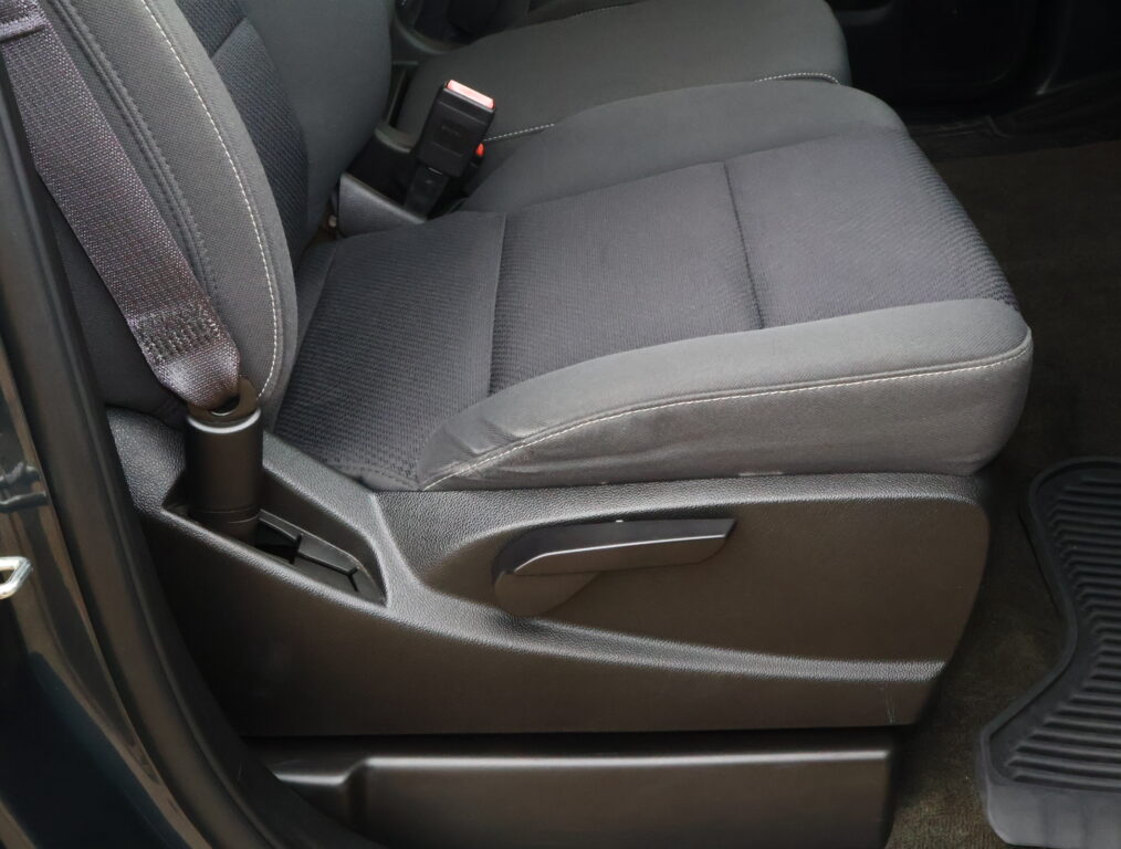 Dark gray car front seat with visible red seat belt buckle between the seat and center console.