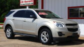 Silver SUV parked in a car lot next to a white building with red trim; a dealership sign reads '12 Month/12k Mile LTD Warranty' and the windshield shows 'Easy Payments'