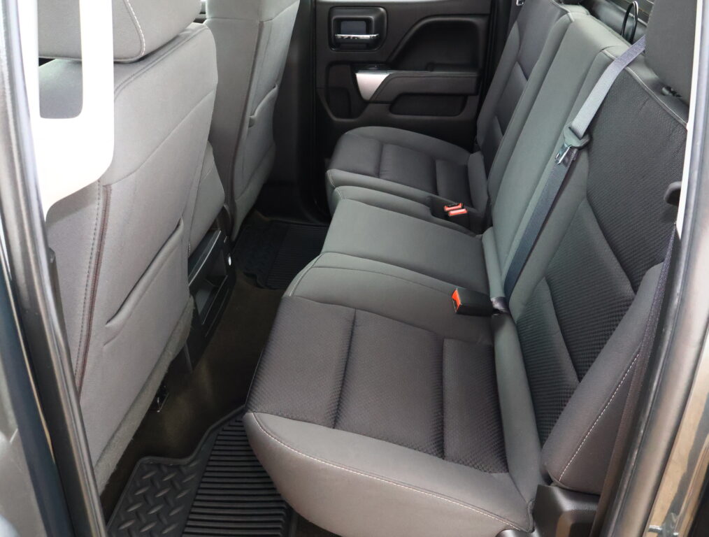 Rear passenger seating area of a vehicle with gray fabric seats, visible seat belts, and door panel.