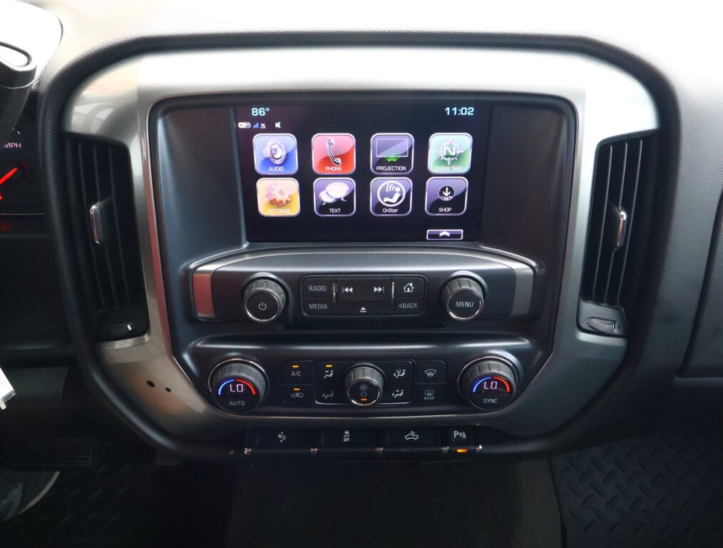 In-car touchscreen showing app icons (Audio, Phone, Projection, OnStar Nav, Settings, Text, OnStar, Shop) with climate controls below.