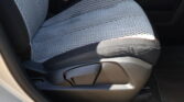 Light gray perforated car seat with red stitching, photographed from the door side, showing the seat and part of the center console.