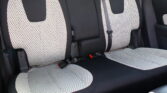 Rear car seats with light perforated fabric and black edges, red stitching visible.