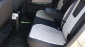 Rear car seat area with two-tone perforated light-gray fabric and center armrest with cup holders, red stitching on the seats