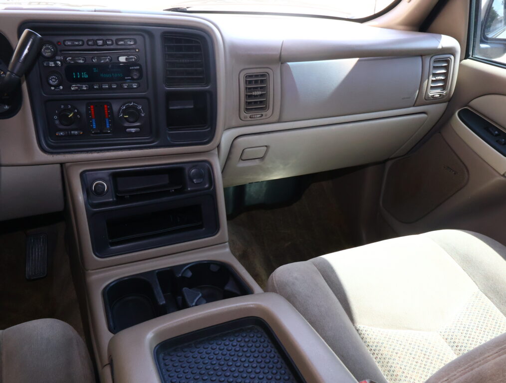 Inside view of a beige SUV dashboard with radio, climate controls, vents, and front passenger seat visible.