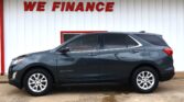 Grey Chevrolet Equinox parked in front of a white wall with a red 'WE FINANCE' sign.