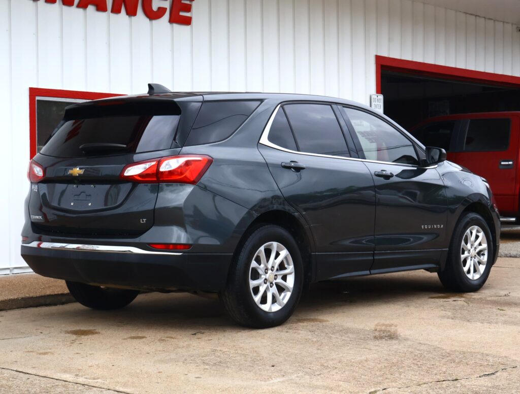 Dark gray Chevrolet Equinox LT parked outside a white building with red trim, rear and side view visible