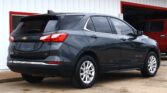 Dark gray Chevrolet Equinox LT parked outside a white building with red trim, rear and side view visible