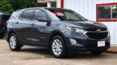 Dark gray Chevrolet Equinox SUV parked in front of a white building with red trim and a Dillon Auto Sales sign
