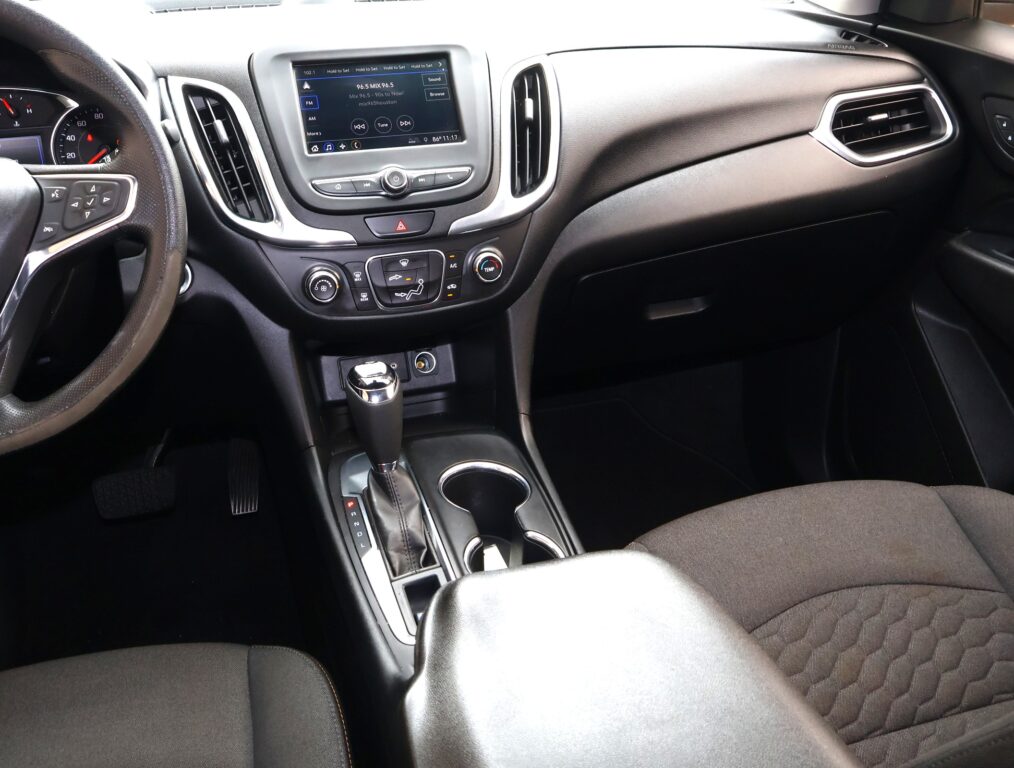 Interior of a car cabin focusing on the center console with a touchscreen display and gear lever area