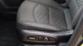 Front driver's seat inside a car, showing quilted dark fabric with orange-stitch detailing and the seat adjustment controls on the lower side edge.