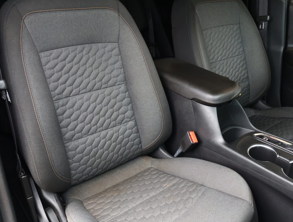 Front car seats with black quilted fabric and orange stitching, center armrest between them