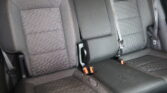 Rear car seat row with dark fabric upholstery, orange contrast stitching, and visible seat belts.