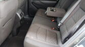Rear passenger seats in a dark fabric car, center armrest folded down with built-in cup holders