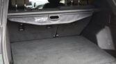Open SUV trunk with cargo cover extended, showing a flat dark carpeted cargo area and folded rear seats in the background