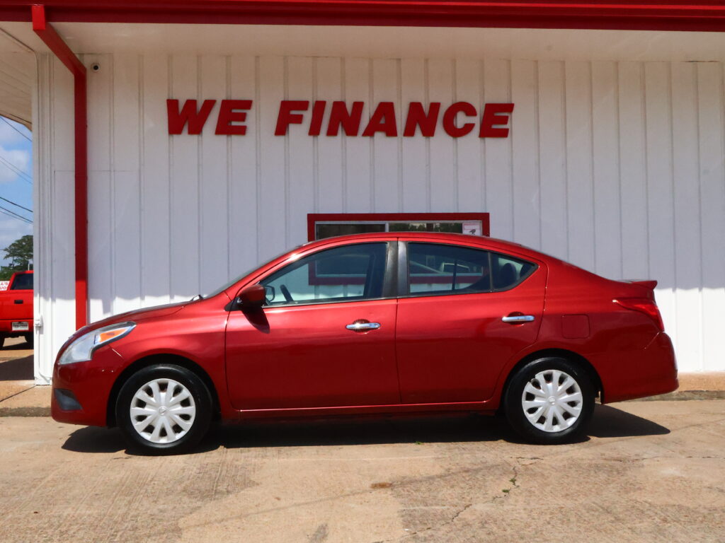 Red car parked in front of a white building with red trim and a bold 'WE FINANCE' sign above.