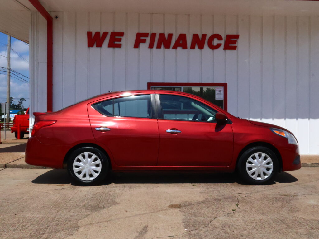 Red sedan parked in front of a white building with a large red 'WE FINANCE' sign above it.