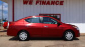 Red sedan parked in front of a white building with a large red 'WE FINANCE' sign above it.