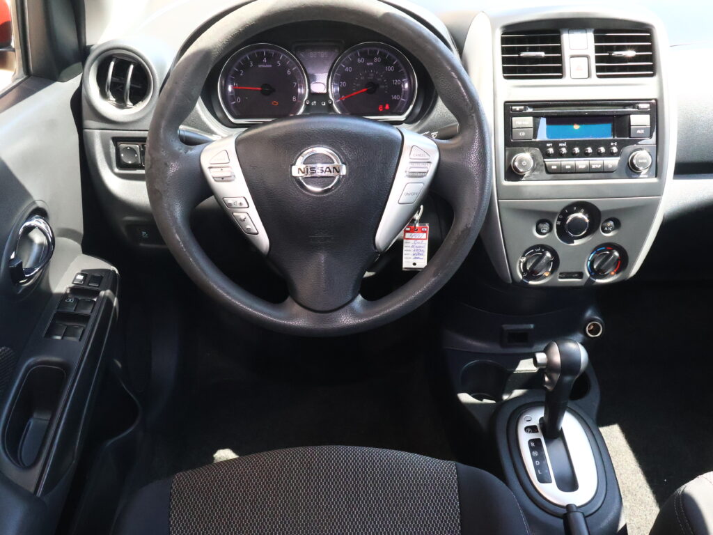 Driver’s cockpit: steering wheel with Nissan emblem, instrument gauges, and center console with radio and climate controls visible.