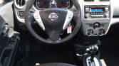 Driver’s cockpit: steering wheel with Nissan emblem, instrument gauges, and center console with radio and climate controls visible.