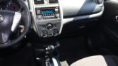 Interior of a car cockpit: steering wheel on the left, central dashboard with radio and climate controls, gear shift lever in the foreground, and front seats.