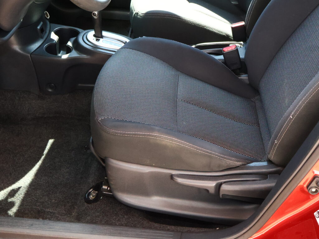 Front passenger seat in a car with a red seat belt buckle visible and the center console nearby.