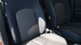 Dark car interior showing front seats with black fabric upholstery and dotted center panels, white contrast stitching.