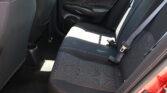 Backseat of a car with dark fabric seats and light stitching, visible seat belts and door panel.