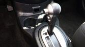 Close-up of a car's automatic shifter with P R N D gear indicators visible and a surrounding center console area.