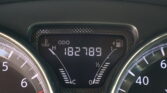 Close-up of a car dashboard instrument cluster showing the speedometer, fuel gauge, and temperature indicators in white on black.