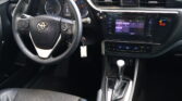 Interior of a car cab showing a steering wheel with Toyota emblem, digital instrument cluster, and center touchscreen infotainment panel.