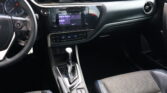 Interior view of a car dashboard showing a touchscreen infotainment system and center console with gear shifter and cup holders