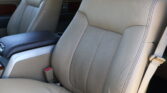Beige leather car seats with cracked creases and a dark center console armrest visible between the seats