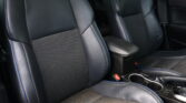 Black leather car seats with blue contrast stitching and a perforated center panel, showing a spacious back seat area and cup holders in the center console.