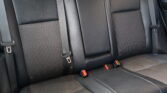 Black leather rear car seats with three seat belts and a center armrest.