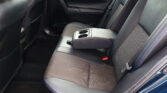Back seat of a dark car interior with a center armrest that folds down to reveal two cup holders.