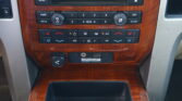 Wood-paneled car dashboard center console with radio, navigation, and climate control buttons.