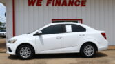 White sedan parked in front of a light-gray wall with large red WE FINANCE letters behind it