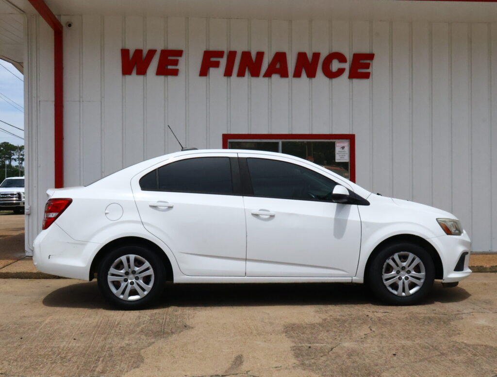White car parked in front of a light-colored wall with a bold red 'WE FINANCE' sign above.