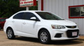 White Chevrolet sedan parked in front of a dealership building with red trim and a Dillon Auto Sales sign.