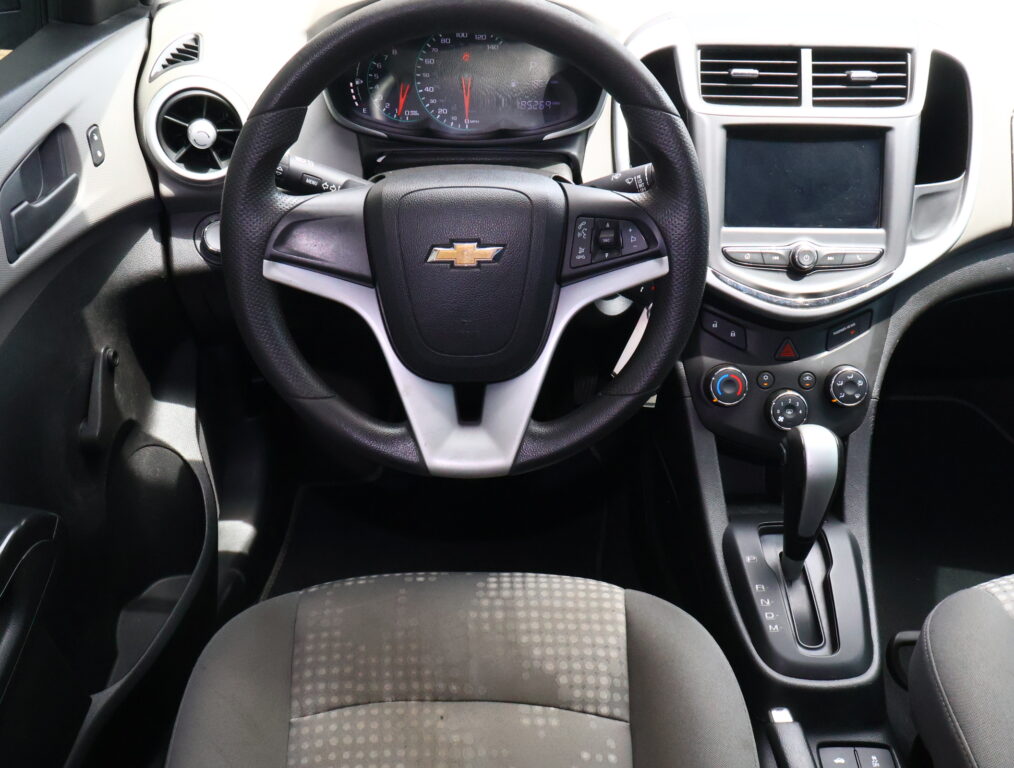 Front interior view of a Chevrolet car showing the steering wheel with logo, instrument cluster, center touchscreen, and climate controls.